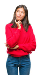 Sticker - Young asian woman wearing winter sweater over isolated background with hand on chin thinking about question, pensive expression. Smiling with thoughtful face. Doubt concept.