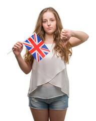 Sticker - Young blonde woman holding flag of UK with angry face, negative sign showing dislike with thumbs down, rejection concept