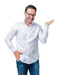 © Krakenimages.com - Handsome middle age elegant senior business man wearing glasses over isolated background smiling cheerful presenting and pointing with palm of hand looking at the camera.