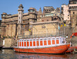 Colorful boat parked in front of Brij Rama Palace-Ancient building on Darbhanga ghat in Varanasi, convereted into a five star hotel. Text in reginal language means name 'Darbhanga Ghat'.