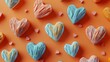   A group of heart-shaped cookies rests atop an orange table, near a heart-shaped cookie cutter