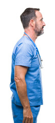 Poster - Middle age hoary senior doctor man wearing medical uniform over isolated background looking to side, relax profile pose with natural face with confident smile.