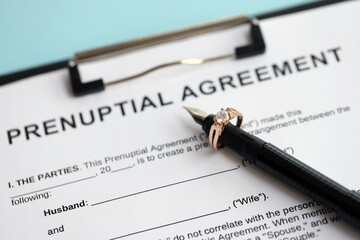 Prenuptial agreement and wedding ring on table. Premarital paperwork process close up