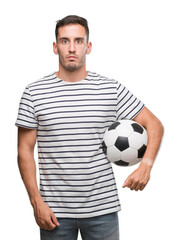 Canvas Print - Handsome young man holding soccer football with a confident expression on smart face thinking serious