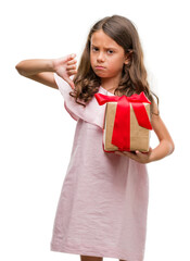 Poster - Brunette hispanic girl holding a gift with angry face, negative sign showing dislike with thumbs down, rejection concept