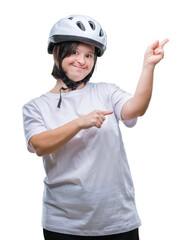 Poster - Young adult cyclist woman with down syndrome wearing safety helmet over isolated background smiling and looking at the camera pointing with two hands and fingers to the side.