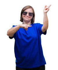 Wall Mural - Young adult woman with down syndrome wearing sunglasses over isolated background smiling and looking at the camera pointing with two hands and fingers to the side.