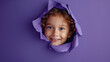 © MIA Studio - A smiling American kid peeking through a hole in a deep purple paper wall providing ample space for messaging