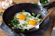 Fried eggs with vegetables on pan
