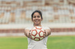 Portrait of woman holding soccer ball and standing on sports field