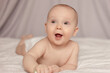 Portrait of a happy baby 7-9 months old,  Infant  baby lying on tummy propped up on arms, small child nursery