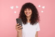 Long distance love. Woman chatting with sweetheart via smartphone on pink background. Hearts around her