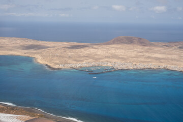 Wall Mural - Views of the island of La Graciosa from the viewpoint of El Rio. Turquoise ocean. Blue sky with big white clouds. Caleta de Sebo. Town. volcanoes. Lanzarote, Canary Islands, Spain