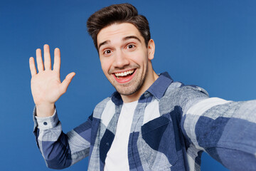 Wall Mural - Close up young man he wears shirt white t-shirt casual clothes doing selfie shot pov on mobile cell phone waving hand isolated on plain blue cyan color background studio portrait. Lifestyle concept.