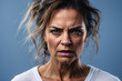 Close-up of an adult woman with an intense and fierce facial expression against a blue background