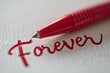 © Wirestock - the pen is writing the word forever in red ink on the piece of paper