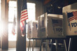 © Kamonwan - American democracy with this image of voting stations arrayed neatly against a wall adorned with patriotic bunting, reflecting the nation's colors.