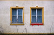 Two windows next to each other of an abandoned house with red coloured window sill