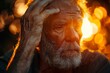 An elderly man contemplates as the orange hue of the setting sun gently caresses his skin and beard