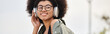 A young woman in a jacket listens to music through headphones while embodying the rhythm in an urban setting.