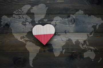 Wall Mural - wooden heart with national flag of poland near world map on the wooden background.