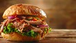 A side angle perspective of a hearty pulled pork sandwich filled with layers of tender meat, lettuce, tomato, and onion