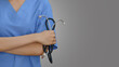 Close-up of a female doctor holding a stethoscope on a gray background.
