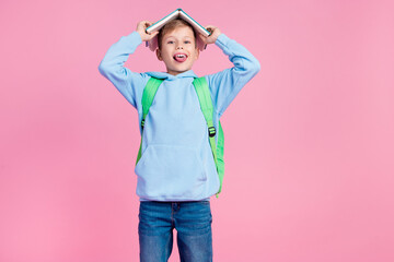 Wall Mural - Photo of positive small boy tongue out hold opened book head roof empty space isolated on pink color background