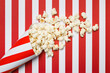 Flat lay composition with popcorn on red and white stripes background.