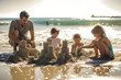 arents and children build intricate sandcastles, framed by the gentle waves on a serene beach.
