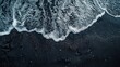 © KAYU - A top view and flat lay of a black sand beach with waves and foam.