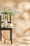 Fototapeta Przestrzenne - home decor and design concept - close up of gypsophila flowers in vase and straw hat on vintage chair over beige background