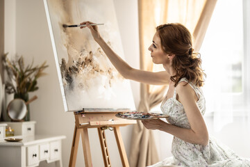 Beautiful female painter enjoying while painting in home art studio. Woman Artist Works on Abstract acrylic painting in the art studio