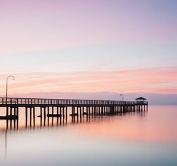 a long wooden pier stretching far out into the vast ocean, surrounded by blue waters and clear skies