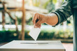 Close-up black male hand putting voting card into the ballot box. Vote on free democratic elections or referendum.