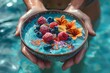 Smoothie bowl in woman hands above swimming pool