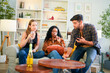 © ultramansk - Group of happy friends laughing and toasting with glasses of champagne in a cozy, sunlit living room at home.