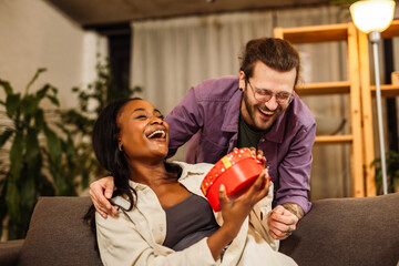 Loving boyfriend surprising his African American girlfriend with a gift.