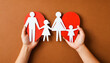 Hands holding heart shape paper family cutout.