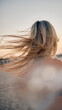 © chika_milan - An evocative scene with a blonde woman's windswept hair by the seaside at golden hour capturing movement and natural beauty