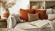 © mashimara - stylish living room during fall, with various textured pillows in shades of orange and brown, a woven throw, and an open book on a modern sofa, creating a tranquil reading nook