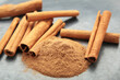 Cinnamon sticks with powder on dark background.
