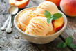 Peach Ice Cream with Fresh Fruit Slices. A bowl of homemade peach ice cream accompanied by fresh peach slices and a mint leaf.	
