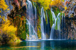 Waterfall over mossy green rocks, fall foliage