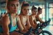 People biking in Spinning class at modern gym, exercising on stationary bike. A sporty lifestyle