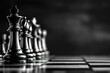 Monochrome photo of chess pieces on wooden board in darkness