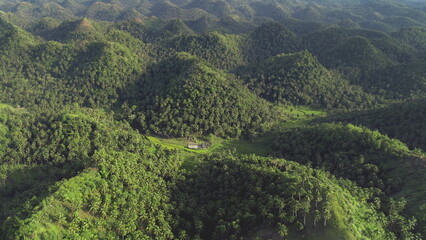 Wall Mural - Philippines green jungle mountains aerial view. Small farm building at hillside grassy valley. Asian tropical rural scenery. Nobody Filipino tropic nature landscape in cinematic drone shot