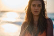 Woman's intense gaze with the beautiful sunset and ocean bokeh in the background