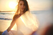 A serene photo of a woman on the beach during sunset, with sunlight creating a lens flare effect