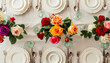 Festive table setting with roses in bright colors and vintage crockery on a beige background
